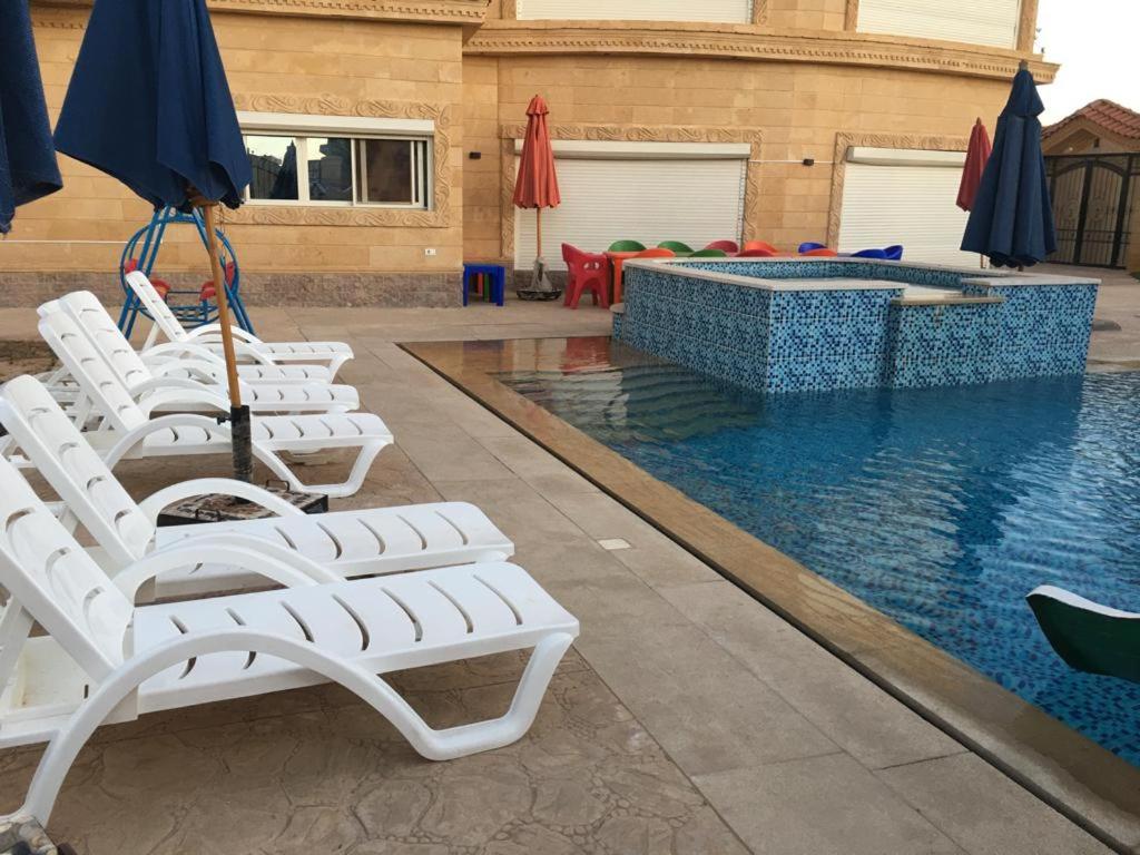 un grupo de sillas y sombrillas junto a una piscina en الريف الاوروبي, en Seis de Octubre