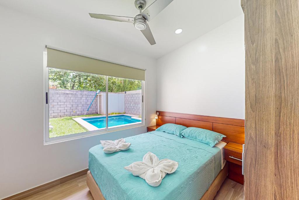 1 dormitorio con cama y ventana con piscina en Casa Eureka, en Herradura