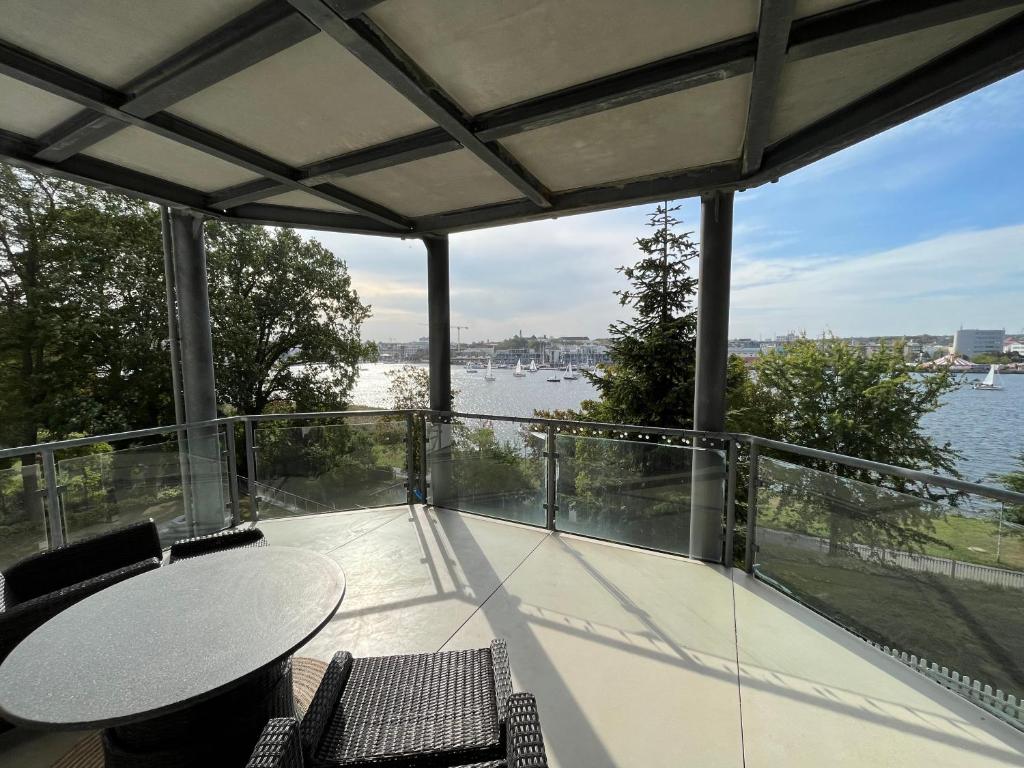 een balkon met een tafel en stoelen en uitzicht op het water bij Traumwohnung mit Stadthafen-Panorama! Zwei Schlafzimmer, Parkplatz in Rostock