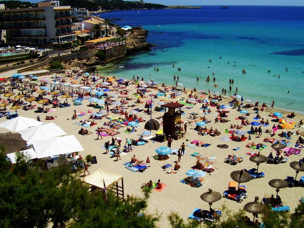 uma grande multidão de pessoas numa praia em Zhimbad B&B by the sea em Cala Ratjada