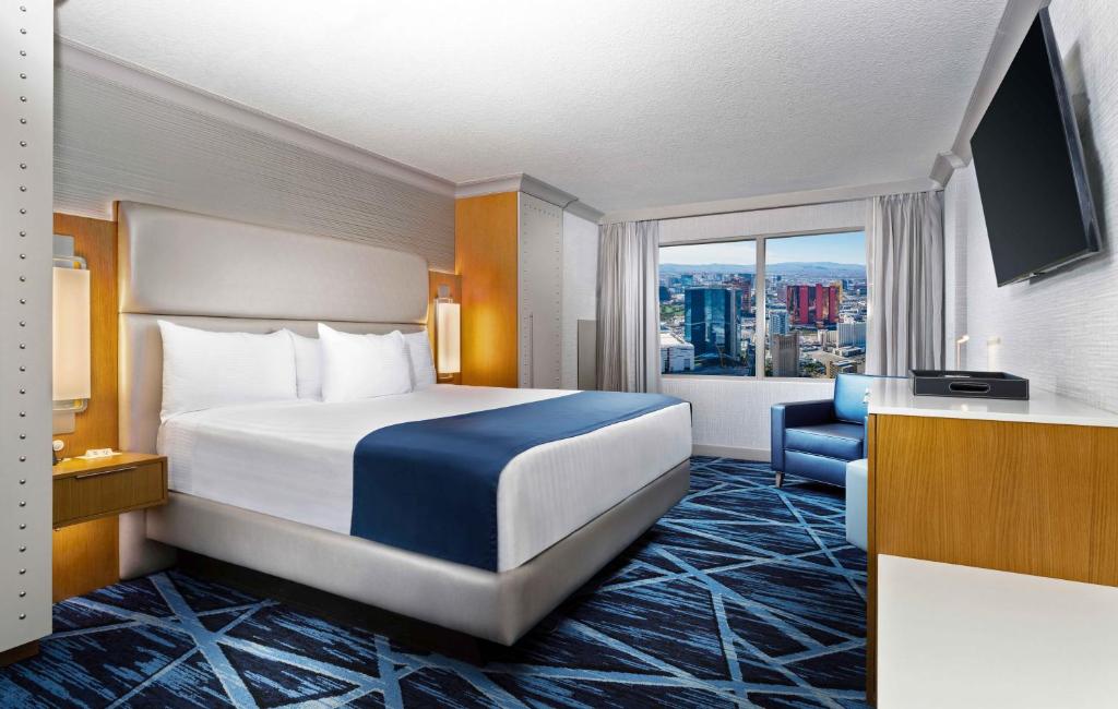 ラスベガスにあるThe STRAT Hotel, Casino & Towerのベッドと大きな窓が備わるホテルルームです。