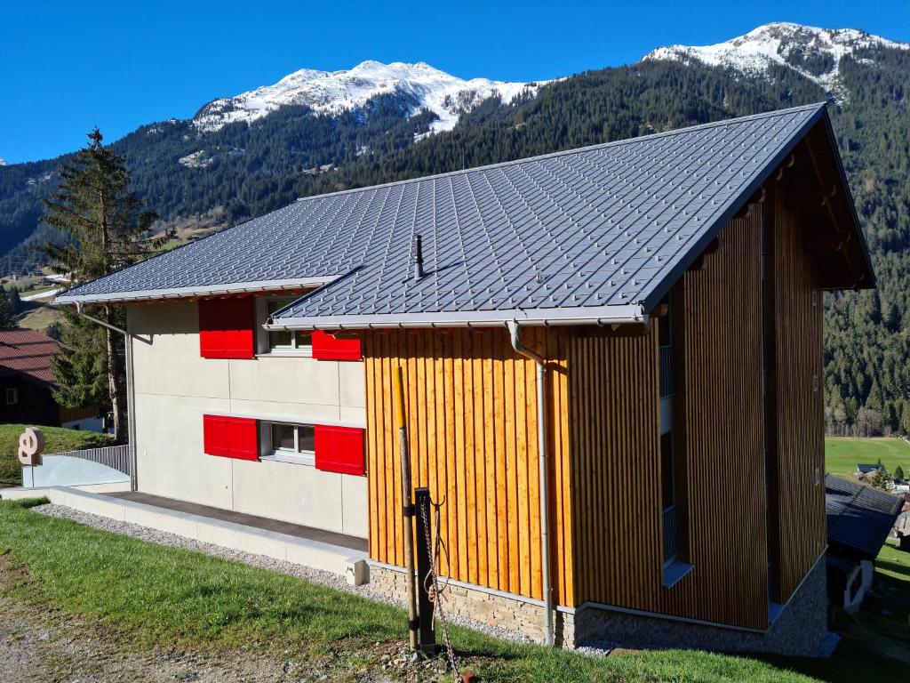 um edifício com uma parede castanha e vermelha e montanhas em Chesa Bunita Trais em Gaschurn