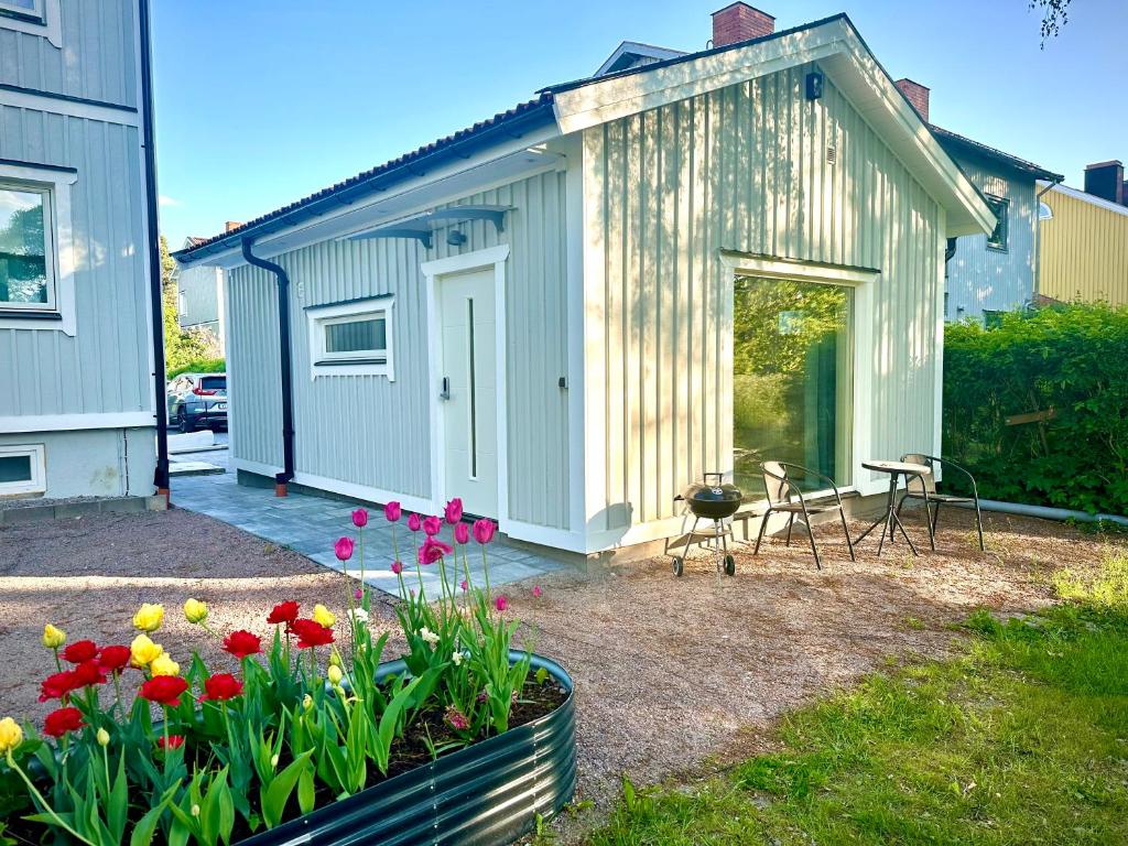 un pequeño cobertizo con mesa, sillas y flores en Park House Gävle - a modern renovated house in the park - 5A, en Gävle