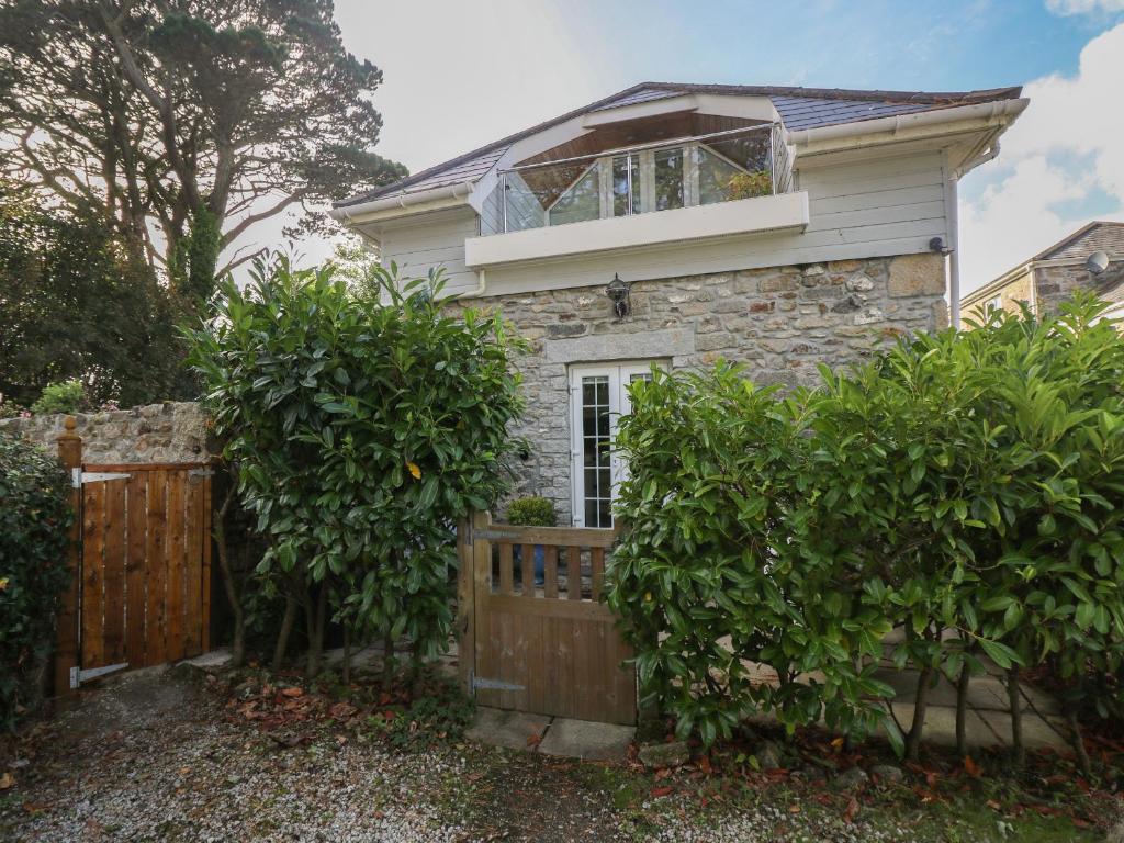 a house with a wooden gate and a fence at Poppyfields Stable in Redruth