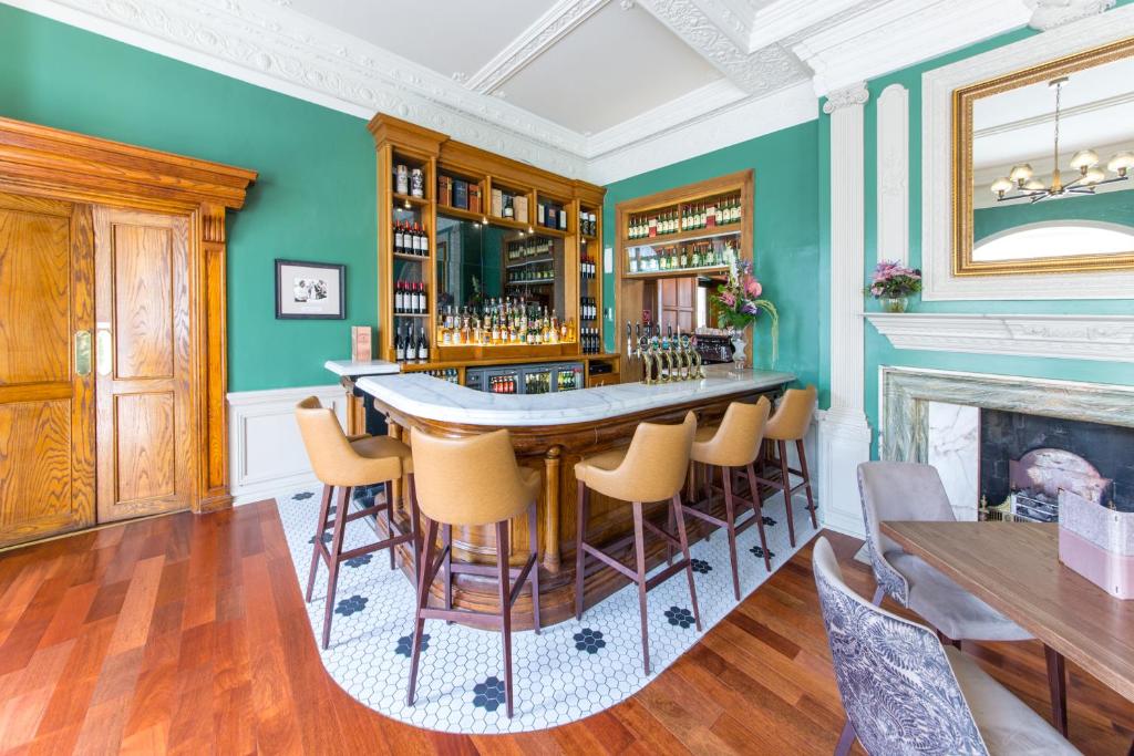 a bar in a room with green walls and a fireplace at Portmarnock Resort & Jameson Golf Links in Portmarnock