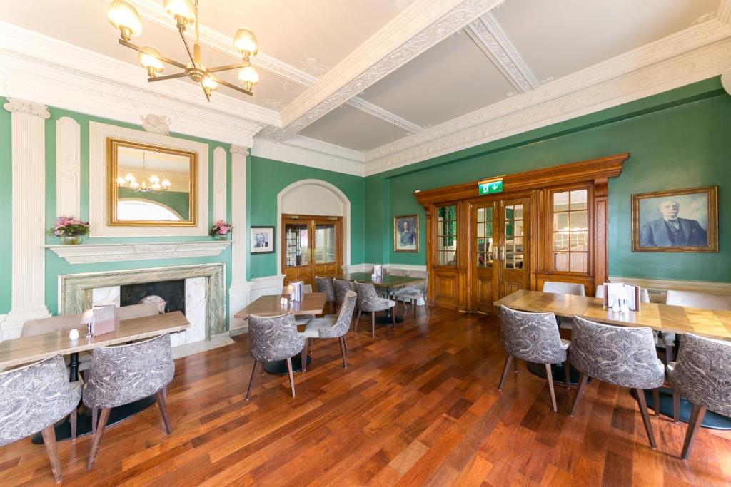 a dining room with green walls and tables and chairs at Portmarnock Resort & Jameson Golf Links in Portmarnock