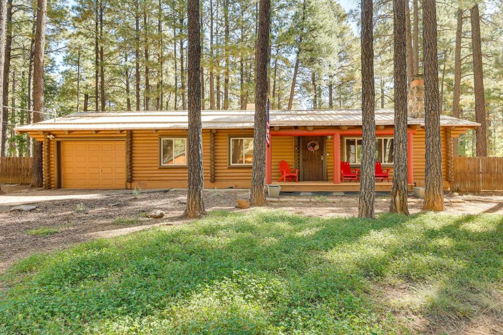 a small yellow cabin in the woods with trees at Pinetop Family Home 11 Miles to Rainbow Lake! in Indian Pine