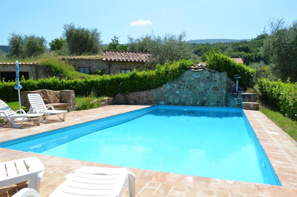 a swimming pool in a yard with two lawn chairs at Casetta del Pozzo in Seggiano
