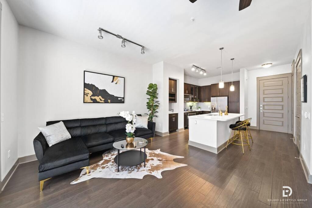 uma sala de estar com um sofá preto e uma cozinha em Downtown Houston Deluxe King Suite with Spa Amenities, Pool and Free Parking em Houston