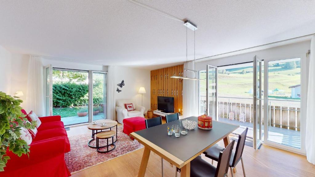 ein Wohnzimmer mit einem Tisch und einem roten Sofa in der Unterkunft Ferienwohnung für 5 Personen Piz Linard Lantsch-Lenzerheide in Lenz