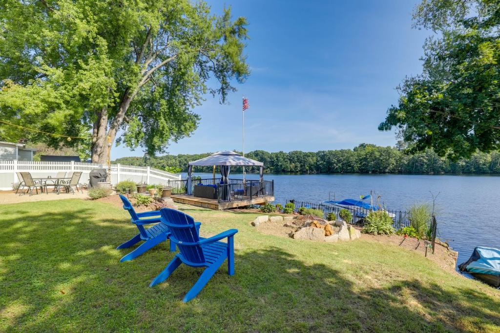 dos sillas azules sentadas en el césped cerca de un lago en Riverfront New Hampshire Cottage with Boat Dock, en Manchester