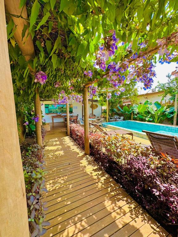 a wooden walkway leading to a pool with flowers at Pousada Ares de Noronha in Fernando de Noronha