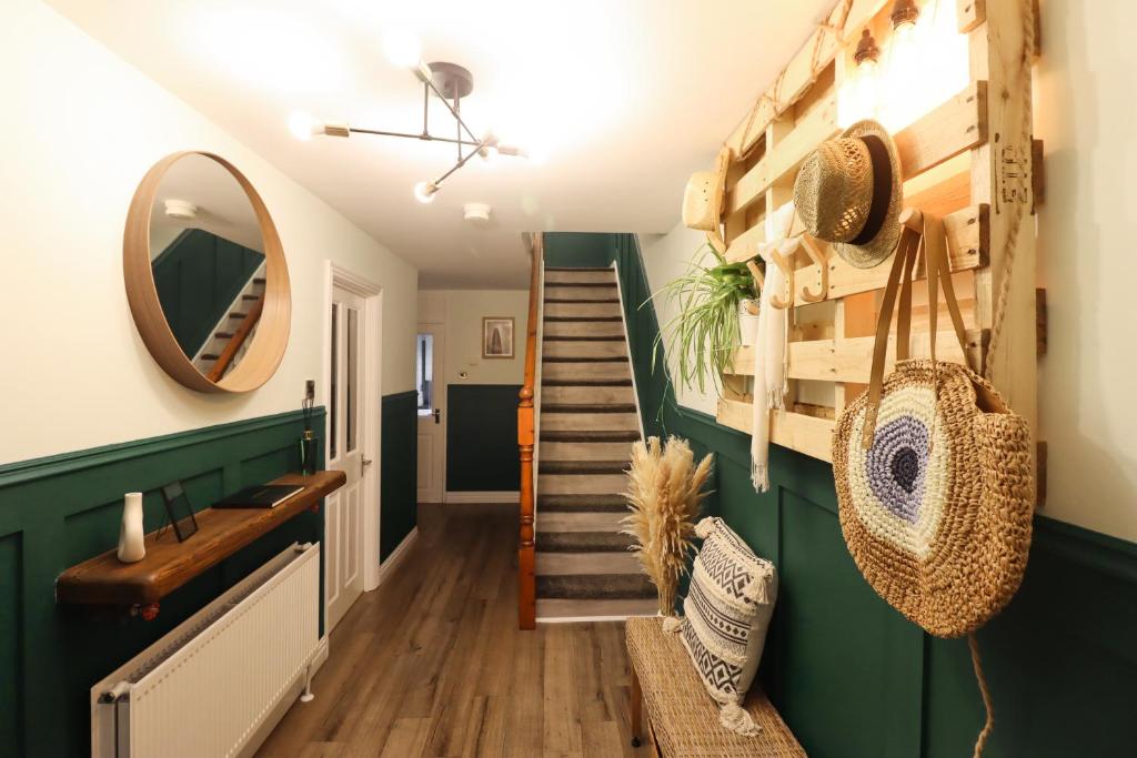einen Flur mit grünen Wänden und eine Treppe mit Spiegel in der Unterkunft A Lil cosy Belfast home in Belfast