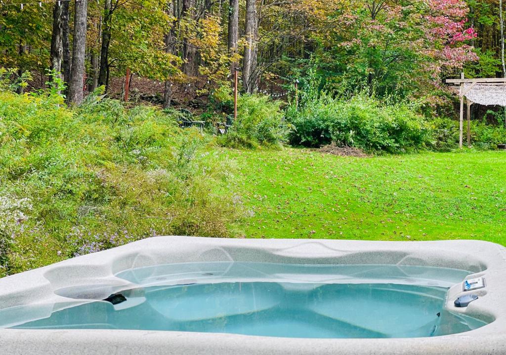 a bath tub in a yard with a garden at Cozy Cottage with Jacuzzi and Fire Pit and Reading Nook! in Livingston Manor