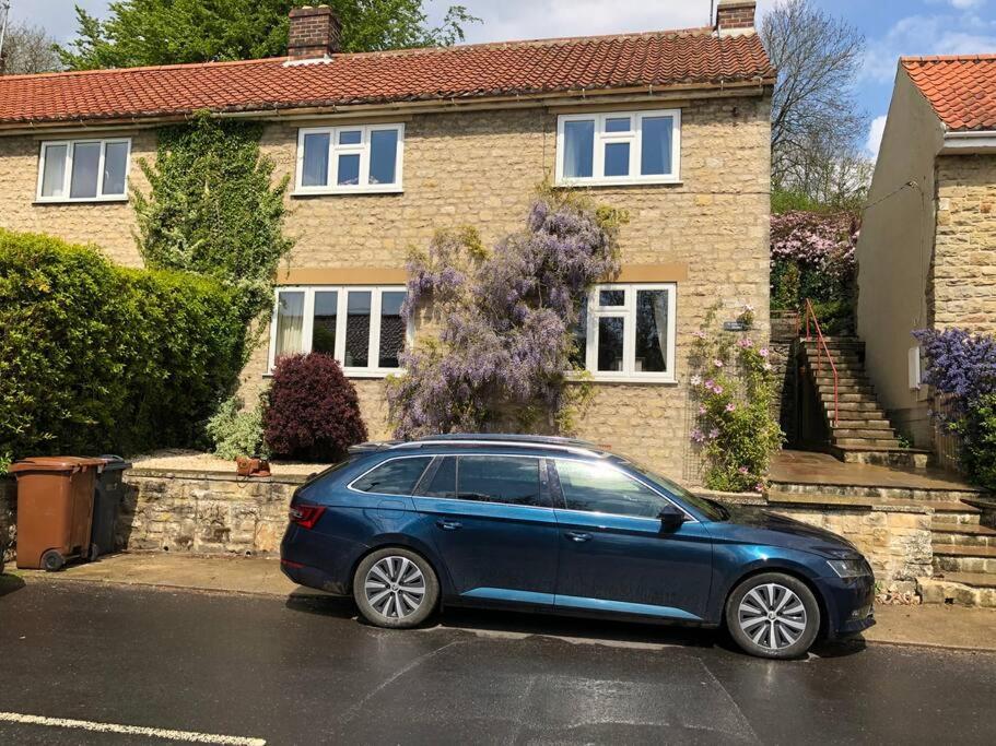 Niebieski samochód zaparkowany przed domem w obiekcie St Anthony’s, bright perkily decorated 3 bedroom house w mieście Ampleforth