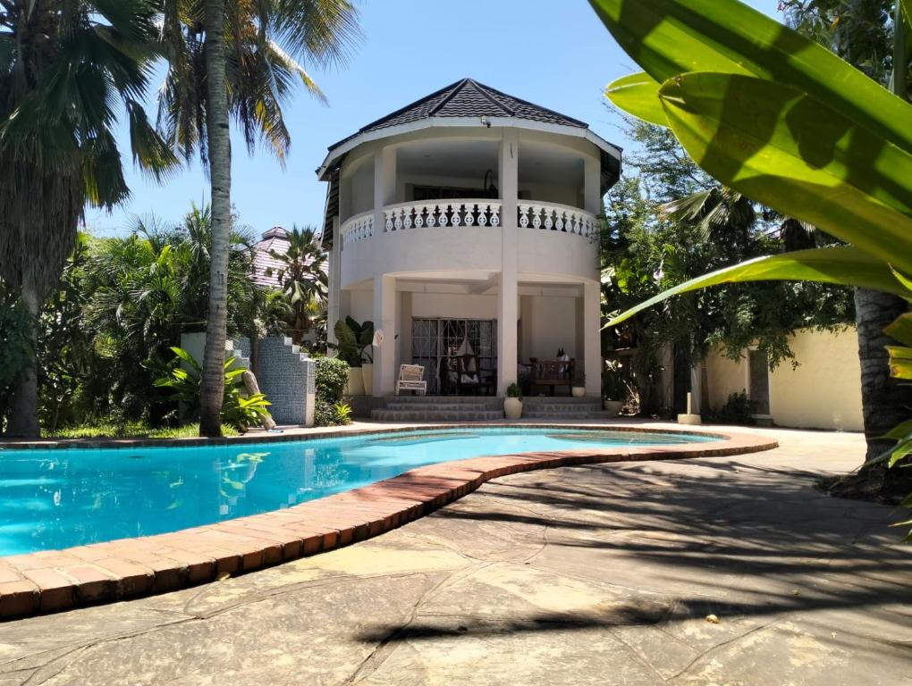 a villa with a swimming pool in front of a house at Diani Hideaway Beach Villa in Galu