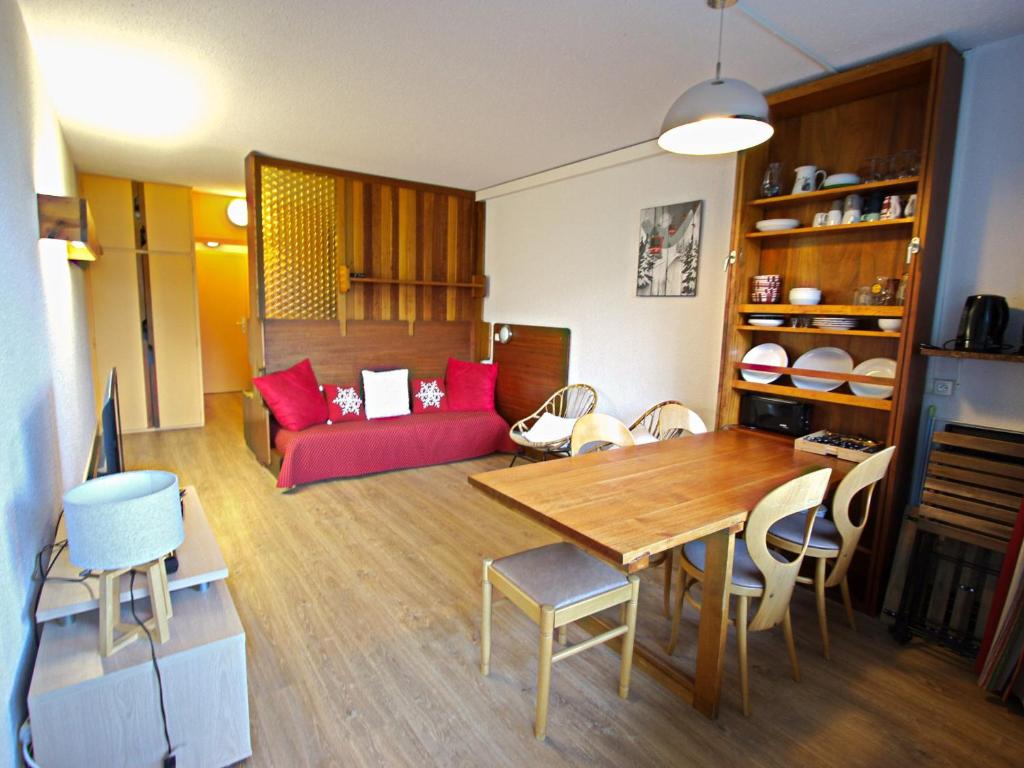 Studio Chamrousse, 1 pièce, 4 personnes - FR-1-549-66 في شامروس: غرفة معيشة مع أريكة حمراء وطاولة