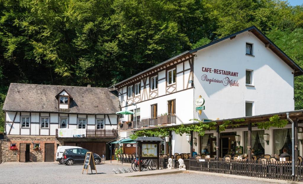 a large white building with people sitting outside of it at Landhotel Ringelsteiner Mühle in Moselkern