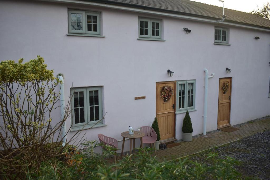 una casa blanca con una mesa y sillas frente a ella en Luxury 2-Bed Barn Conversion in Llansteffan, en Carmarthen