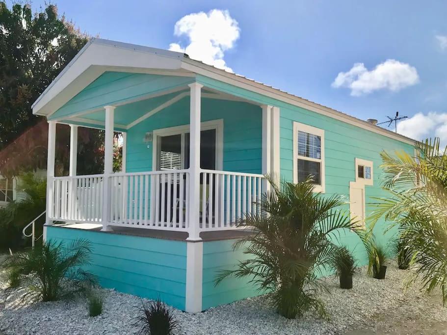 una casa blu con una veranda bianca sulla spiaggia di Pinecraft Blue Heron Tiny Home a Sarasota