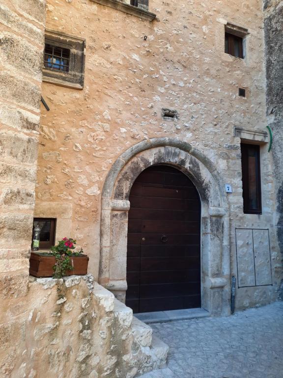 a building with a brown door and a stone wall at Il sogno in Santo Stefano di Sessanio