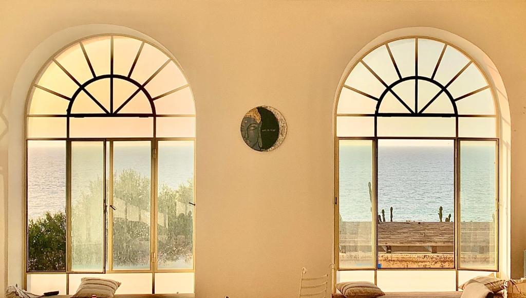 2 ventanas en una habitación con vistas al océano en The Cliff Hotel., en Tel Aviv