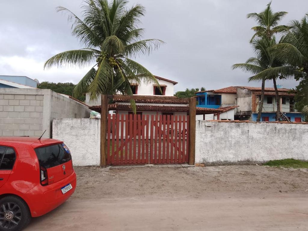 um carro vermelho estacionado em frente a um portão em Casa à 200 metros da praia em Porto Seguro