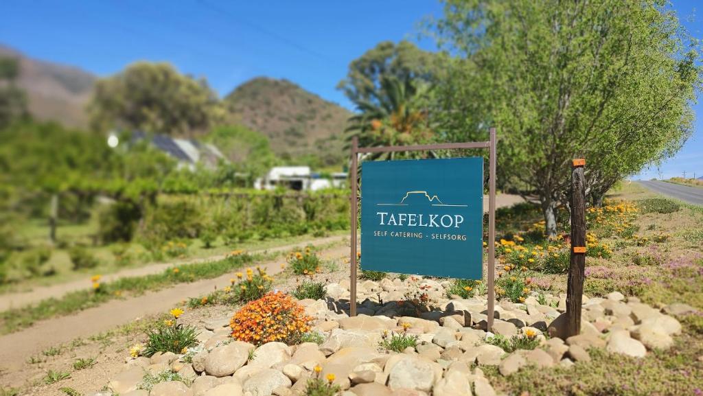 a sign in the middle of a garden with rocks at Tafelkop Keisie Self Catering Cottage in Montagu
