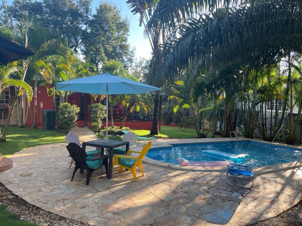 een tafel met stoelen en een parasol naast een zwembad bij Majestuosa villa en Pedro Brand in Pedro Brand