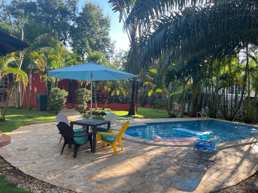 una mesa con sillas y una sombrilla junto a la piscina en Majestuosa villa en Pedro Brand, en Pedro Brand