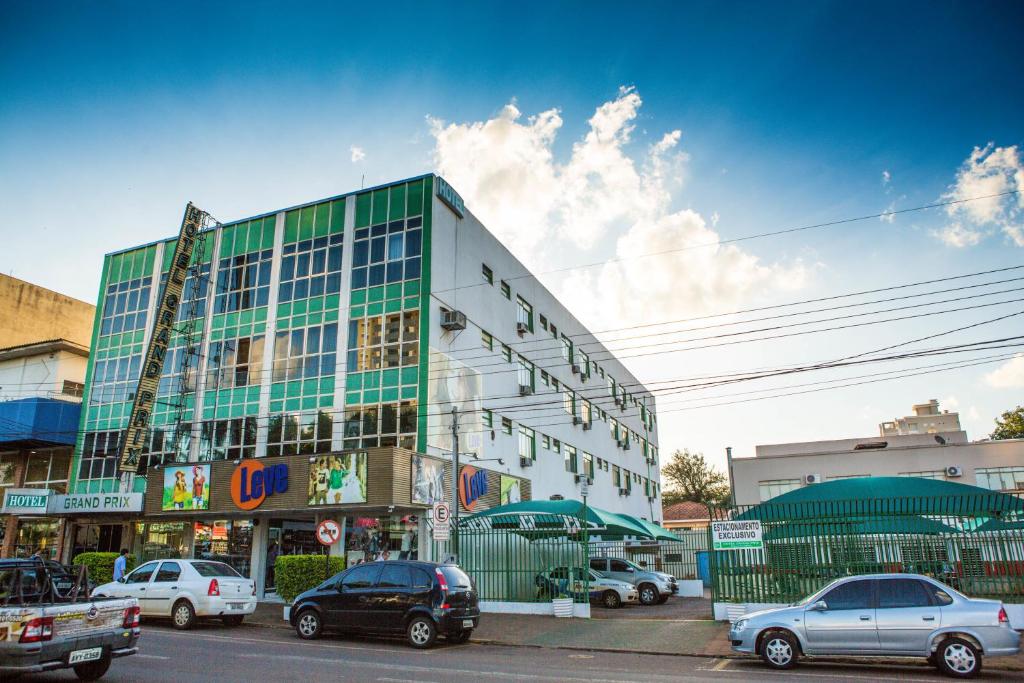 un bâtiment avec des voitures garées dans un parking dans l'établissement Grand Prix Hotel, à Cascavel