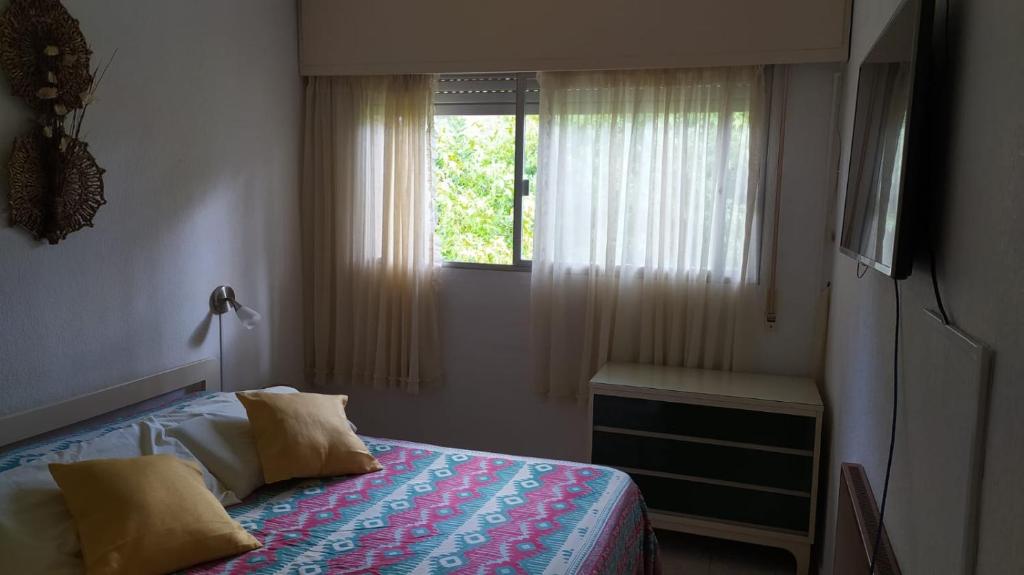 een slaapkamer met een bed en een raam bij Precioso apartamento en un entorno verde y tranquilo en playa mansa in Punta del Este
