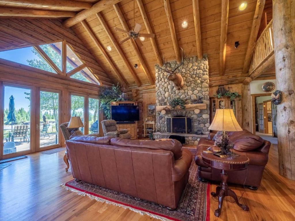 a living room with a leather couch and a stone wall at Sun Valley Cabin in Grand Lake