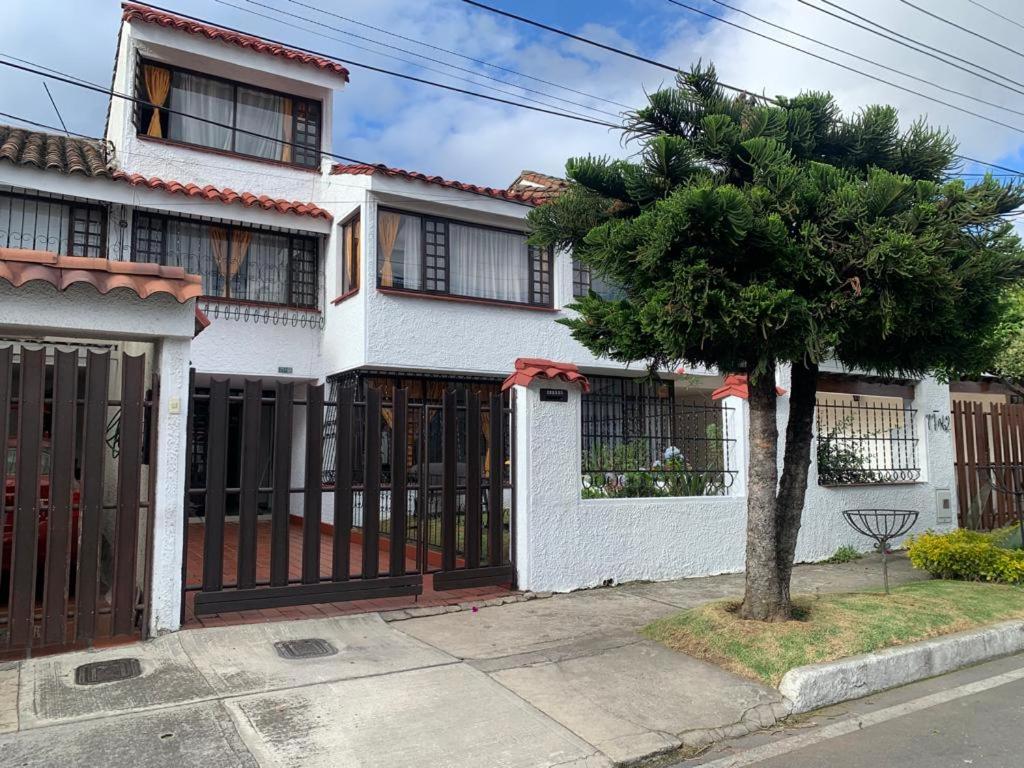 una casa blanca con una puerta y un árbol en Hostal Luxury Bogota, en Bogotá