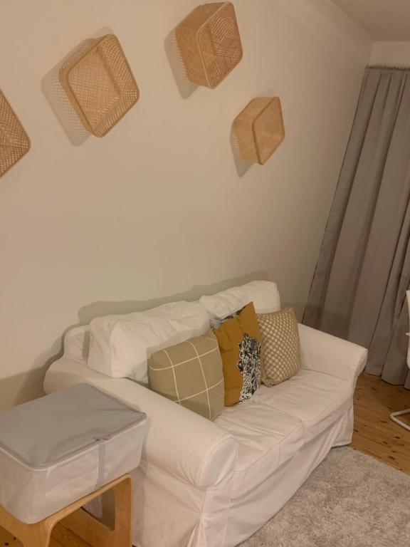 un sofá blanco con almohadas en la sala de estar en Little gem in city, en Linköping