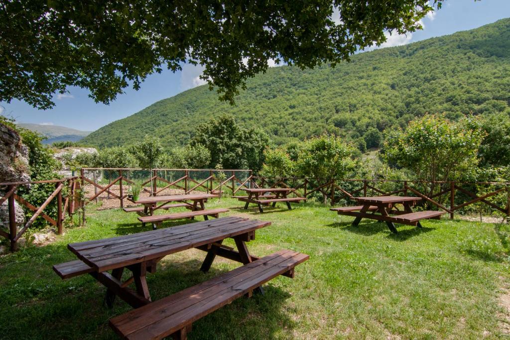 a group of picnic tables in the grass with mountains in the background at Al Peschio Pizzuto Agriturismo in Scanno