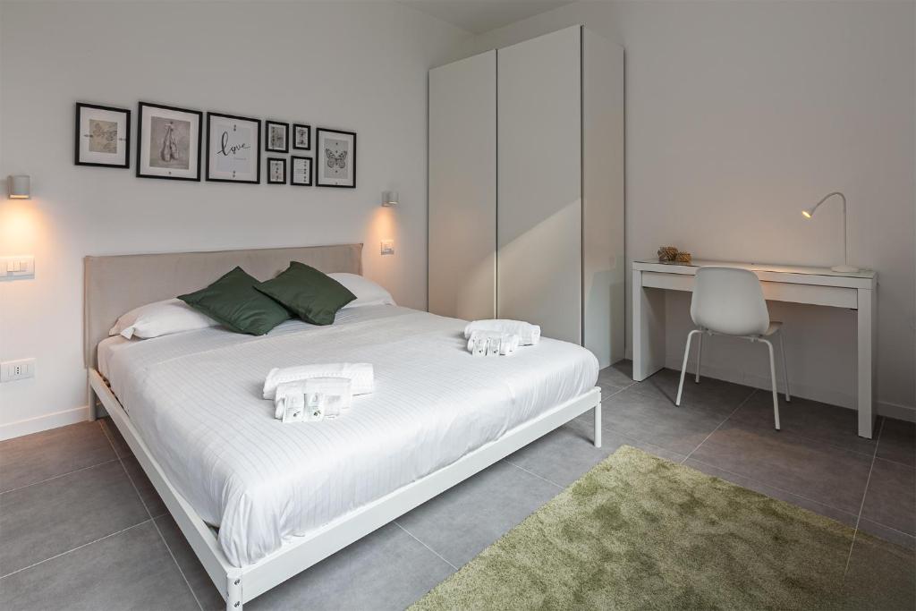 a bedroom with a white bed with a desk and a chair at Le Suites Moderne in Milan