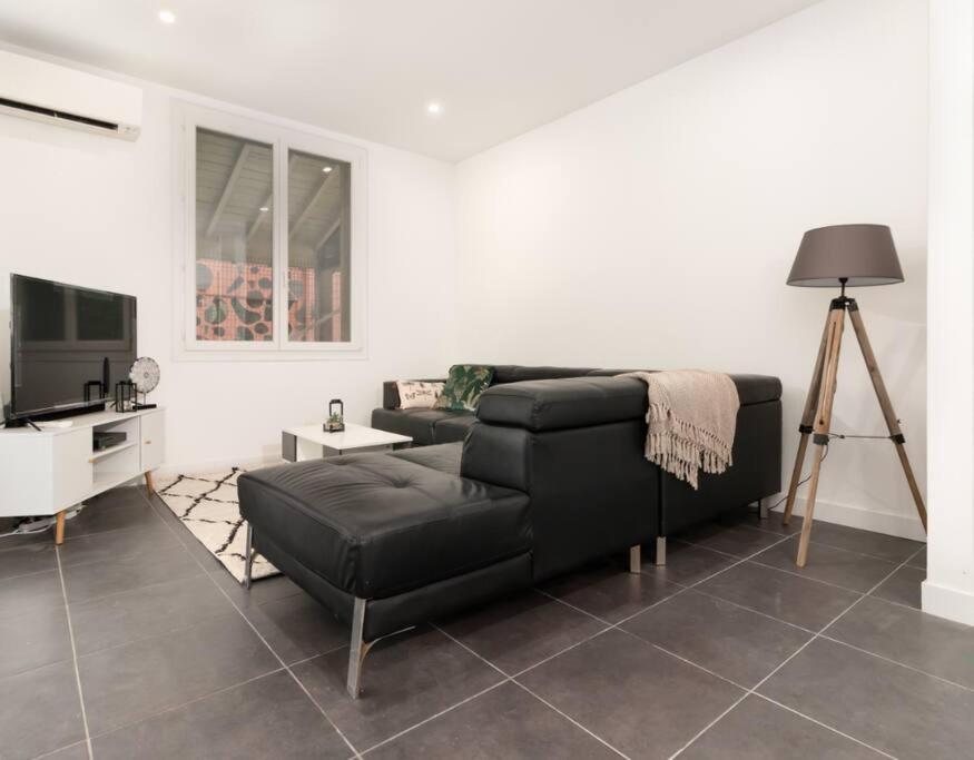 a living room with a black couch and a tv at Chambre qualité hôtel 4 etoiles dans un appartement partagé in Frouzins