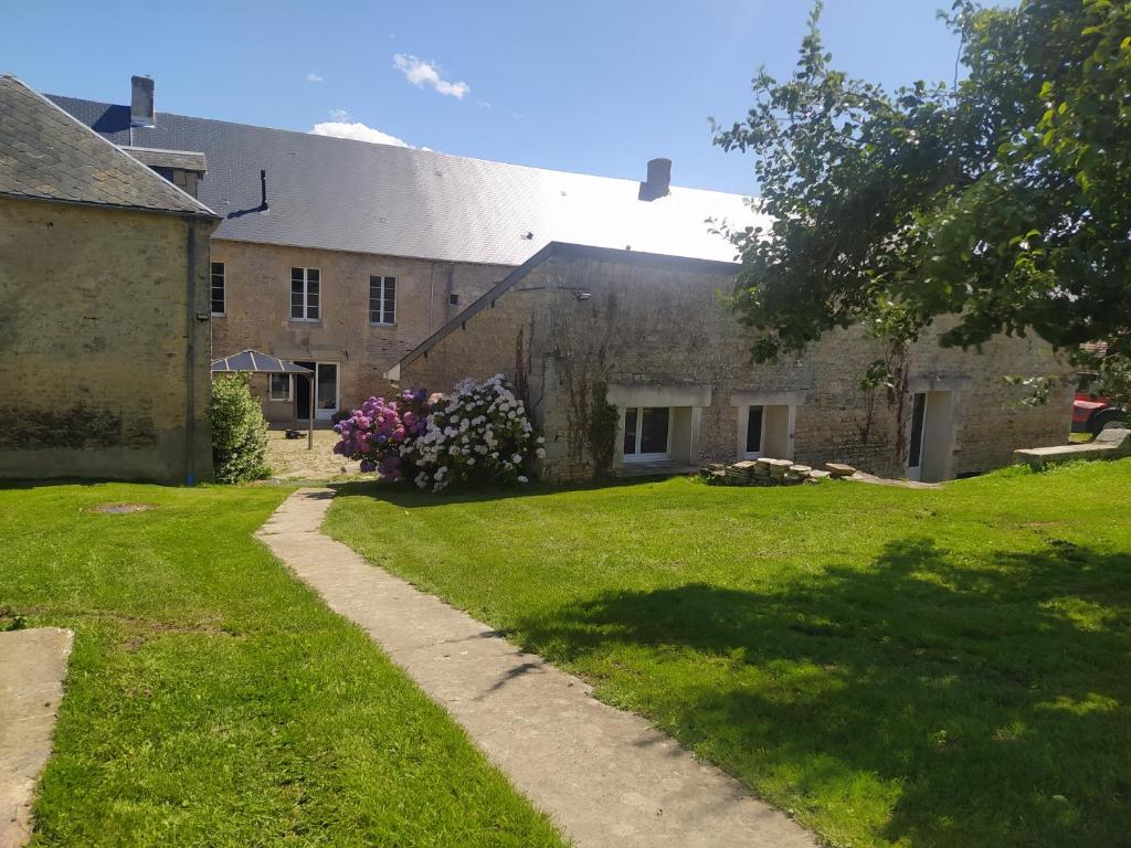 un antiguo edificio de piedra con un patio de césped en CAP MANVIEUX Gîtes en Manvieux