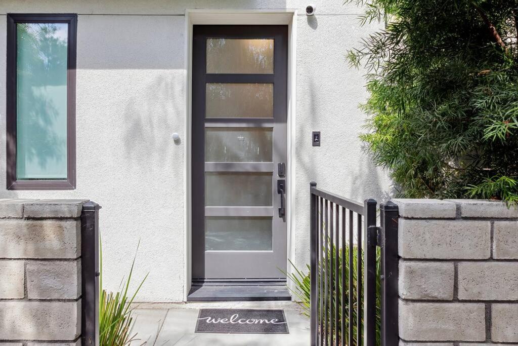 a white house with a door and a fence at Bright, Modern, Central - Theater Room, Sleeps 9 in Los Angeles