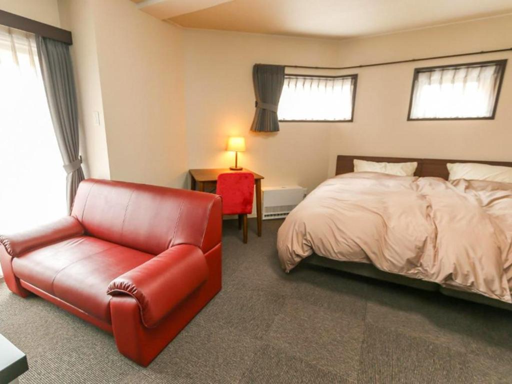 sypialnia z łóżkiem i czerwonym skórzanym fotelem w obiekcie KAMUY RERA - Vacation STAY 62288v w mieście Kushiro