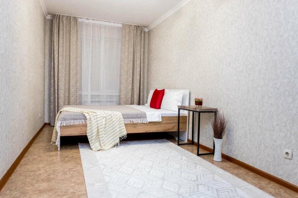 阿拉木圖的住宿－Яркая Квартира на Арбате，一间卧室配有一张带红色枕头的床和窗户