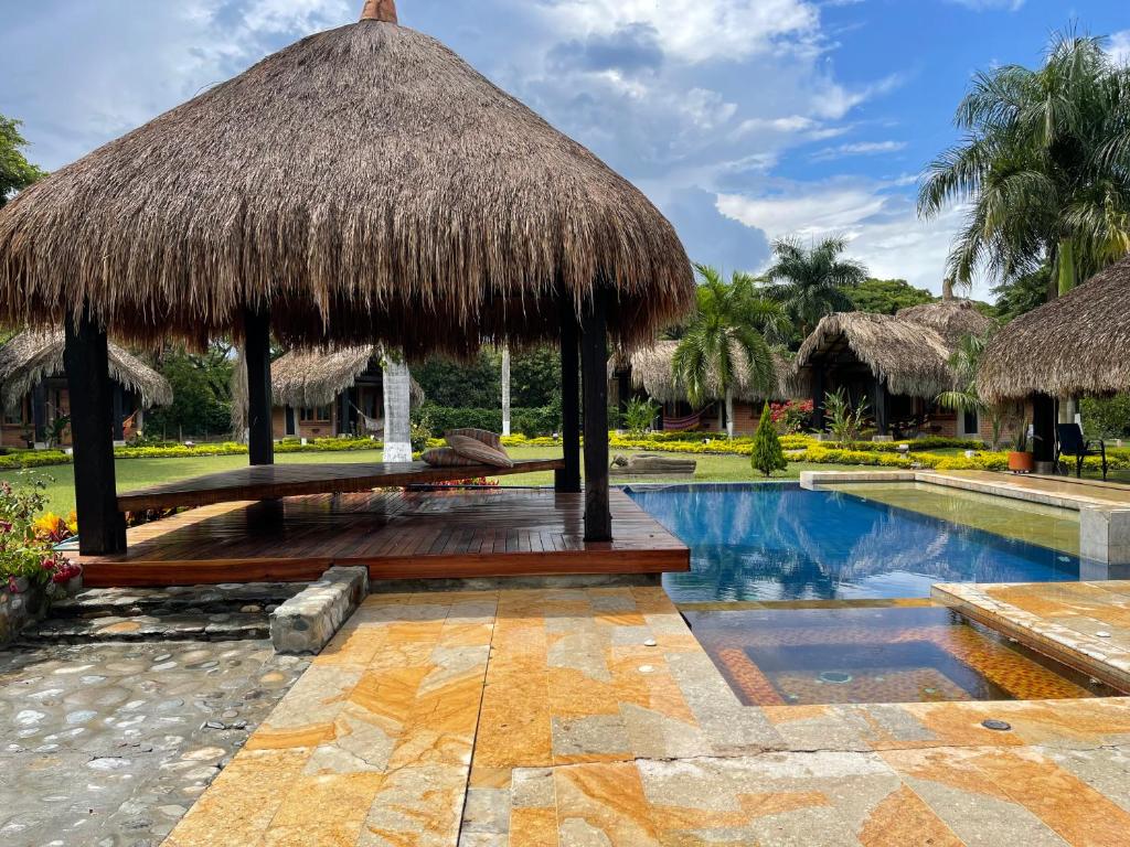 a resort with a pool and a thatch roof at finca playa alta in Palmira