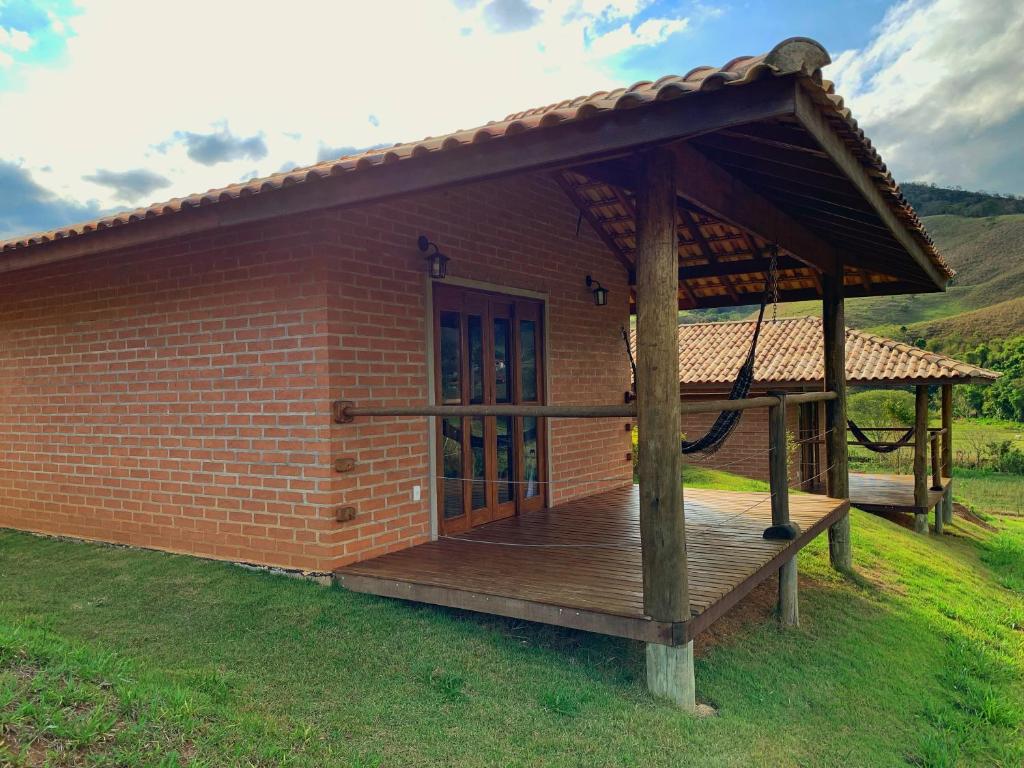 um pequeno edifício de tijolos com um deque de madeira em Chalés Canto da Serra em São Bento do Sapucaí