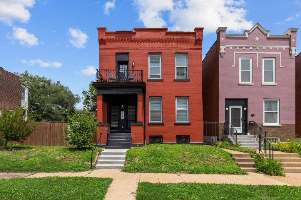 ein rotes Gebäude mit einem Balkon vor zwei Gebäuden in der Unterkunft Red Brick Hideaway | JZ Vacation Rentals in Soulard