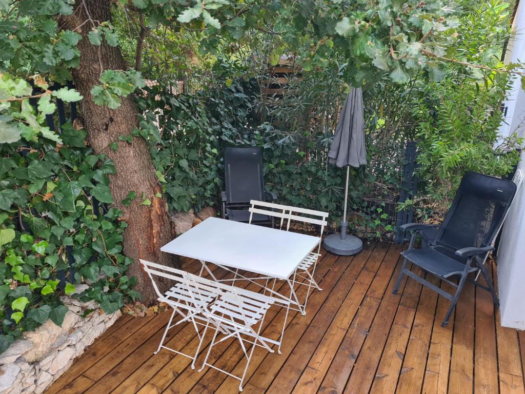 une table, des chaises et un parasol sur une terrasse en bois dans l'établissement Les chênes verts, à Sommières