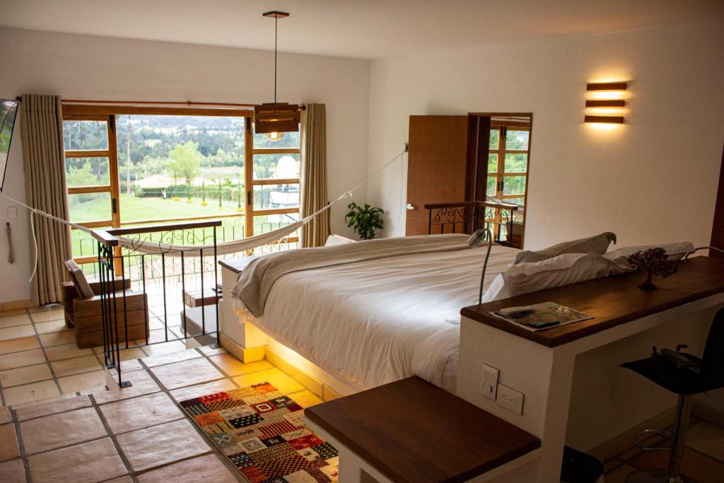 a bedroom with a large bed and a balcony at Hospedaje campestre - El Solaz Suites in Villa de Leyva