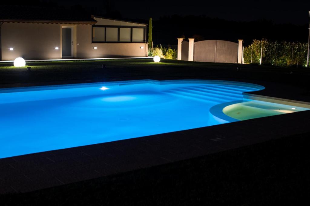 a swimming pool lit up at night with blue lights at Tenuta il Giardino in Capannori