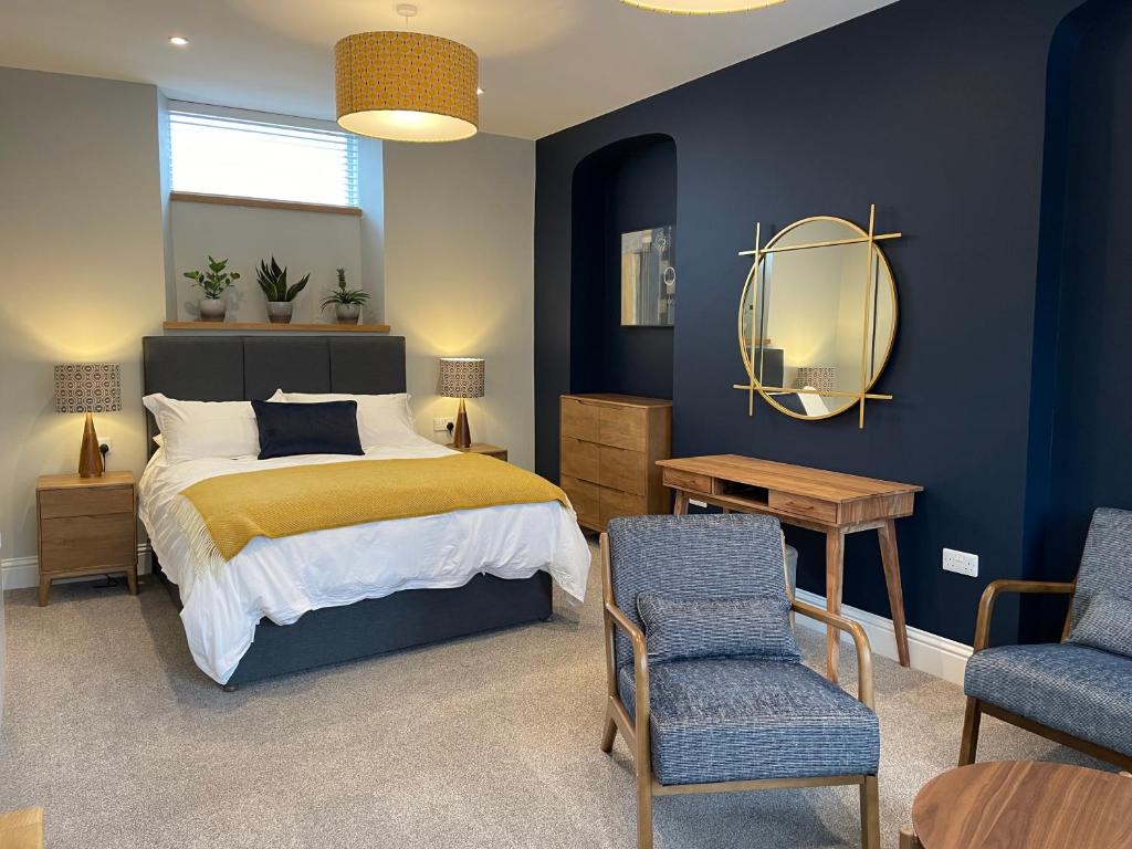 a bedroom with a bed and two chairs and a mirror at Allium in Tenby