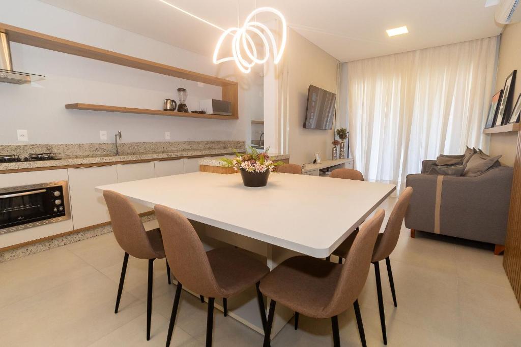 a kitchen and dining room with a white table and chairs at 139C - lindo apartamento a 50m da praia de Canto Grande in Bombas